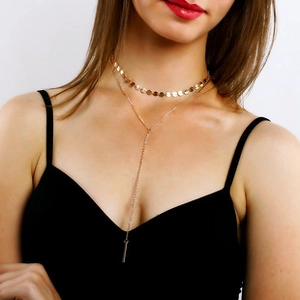 Détail d'un collier doré multicouche avec tour de cou et pendentif barre en forme de Y