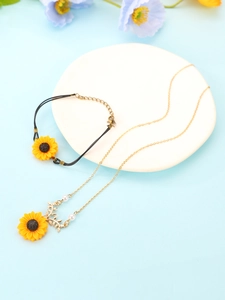 Detailed set of daisy pendant necklace and black woven sunflower bracelet on white plate