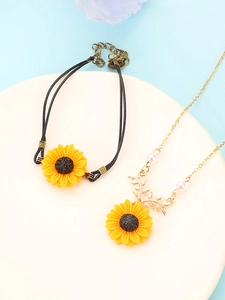 Detail of sunflower bracelet with black cord and matching gold necklace with white pearl
