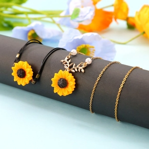 Daisy sunflower necklace and woven bracelet set on elegant gray display stand