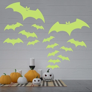Luminous Halloween bat wall stickers on a wooden wall with festive pumpkin decorations