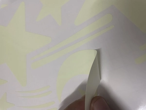 Detail showing self-adhesive glowing moon and star wall stickers peeling from backing