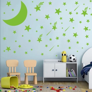 Luminous green moon and stars wall stickers glowing in a cozy blue kids' bedroom setting