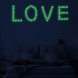Luminous wall stickers showing the word LOVE in fluorescent green glow on a dark wall