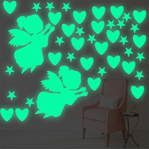 Luminous wall sticker set showing glowing green stars and angels in a dark bedroom