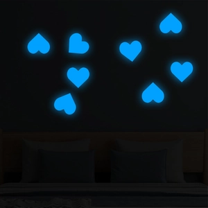 Detailed view of blue glowing heart wall stickers illuminating a bedroom wall in the dark