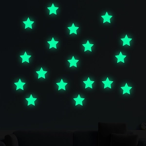 Luminous green star wall stickers glowing in dark room over a sofa silhouette