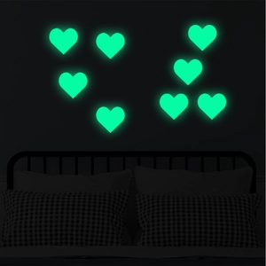 Luminous heart-shaped wall stickers showing bright green glow in dark bedroom setting