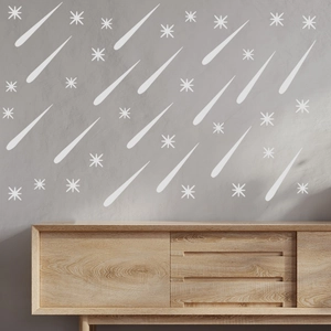 Luminous wall sticker set with falling stars and starbursts on a grey textured wall