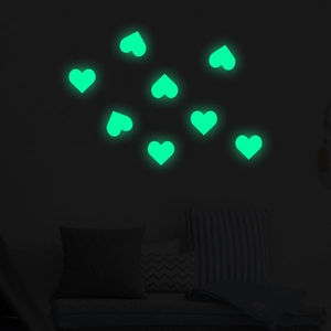 Luminous heart-shaped wall stickers showing bright green glow in dark bedroom