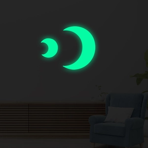 Detailed view of luminous crescent moon wall stickers glowing bright green in a dark bedroom