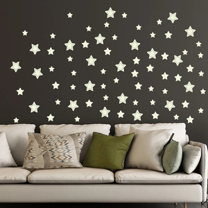 Luminous star wall decals glowing on a dark wall behind a sofa in a modern kids' bedroom