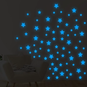Luminous blue star wall stickers glowing in a dark bedroom above a modern sofa