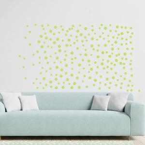 Detail of round luminous stickers on a white wall above a light blue sofa in a bedroom