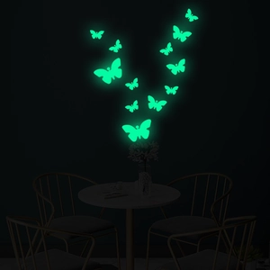 Luminous butterfly wall stickers glowing in green light within a dark living room setting