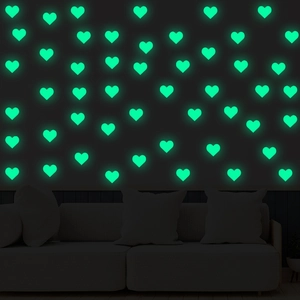 Macro view of glowing heart-shaped wall stickers emitting green light in the dark room