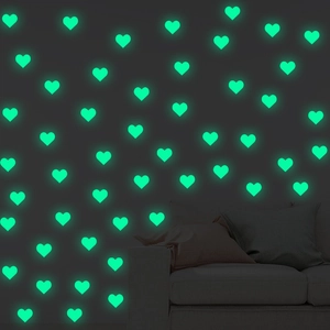 Luminous heart wall stickers glowing green in a dark bedroom setting for home decor