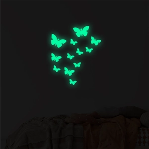 Detailed view of luminous green butterfly wall stickers glowing in a dark bedroom setting