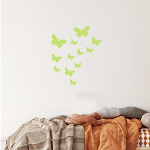 Close-up of luminous butterfly wall stickers glowing green in a cozy bedroom setting