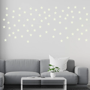 Détail des stickers muraux étoiles lumineuses dans un décor de salon chic et épuré
