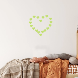 Stickers muraux en forme de cœur lumineux disposés au-dessus d'un lit d'enfant douillet