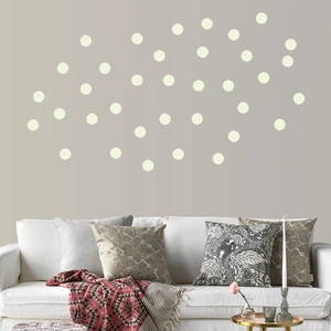 Detailed view of cream white circle wall stickers on a grey wall behind a white sofa