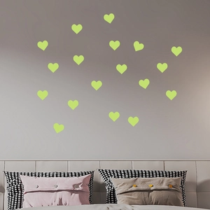 Stickers muraux cœurs luminescents disposés sur le mur de la chambre près du lit
