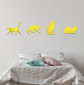 Detail of four yellow acrylic cat mirror wall stickers in various poses on a white wall