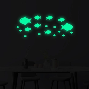 Detail view of glowing green fish wall stickers in a dark room with minimalist decor