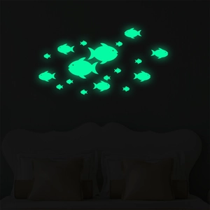 Luminous fish wall stickers glowing in bright green inside a dark bedroom scene