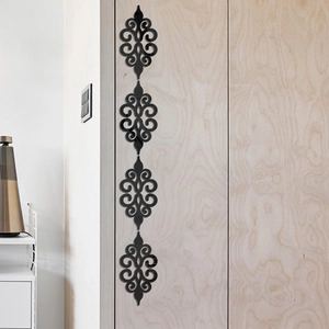 Vertical black acrylic wall stickers with baroque floral pattern on light wood furniture