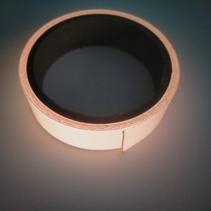 Detailed view of self-adhesive luminous tape roll glowing in bright yellow in dark environment