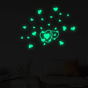 Glow-in-the-dark green heart wall stickers illuminating a dark bedroom wall