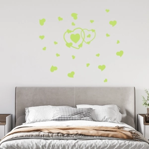 Luminous green heart wall stickers glowing above a cozy bed in a modern bedroom interior