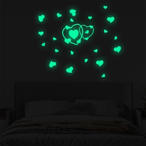 Luminous heart wall stickers glowing in bright green on bedroom wall in total darkness