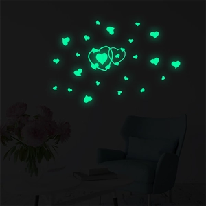 Luminous green heart wall stickers glowing in dark bedroom with furniture background