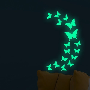 Macro detail of 18 luminous green butterfly wall stickers arranged in a crescent on dark wall