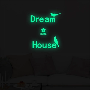 Luminous wall stickers with Dream Home text and birds glowing in a dark room setting