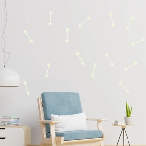 Glow-in-the-dark arrow wall stickers scattered on a white wall above a blue sofa