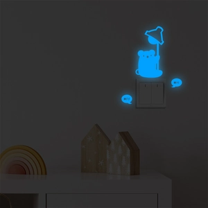 Glow in the dark blue bear wall sticker on a white light switch in dark room
