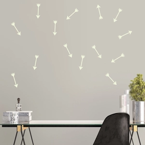Glow-in-the-dark arrow wall stickers scattered on a light gray wall in a modern office