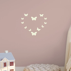 Luminous butterfly wall stickers arranged in a heart shape on a warm pink wall