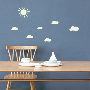 Glow-in-the-dark sun and clouds wall stickers set on a navy blue wall in a modern room