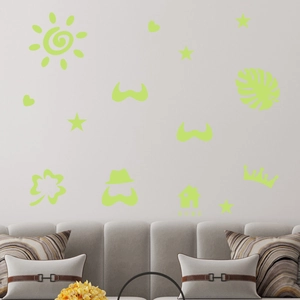 Detailed view of luminous green wall stickers featuring sun, stars and house over a sofa