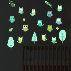 Luminous wall stickers set showing glowing cartoon owls and trees in a dark nursery
