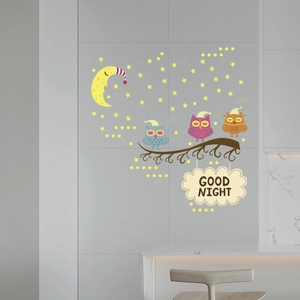 Detailed view of glow-in-the-dark cartoon owl and moon stickers on a gray wall