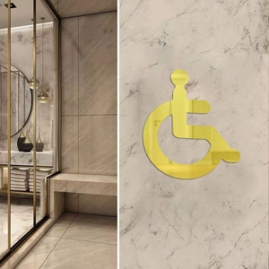 Macro shot of mirror-finish gold acrylic wheelchair accessibility sign for restroom decor