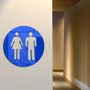 Macro view of a blue mirror acrylic circular restroom sign on a light wall background
