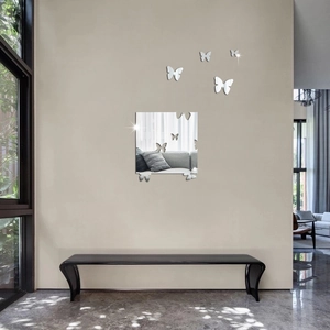 Stickers muraux papillon miroir argenté sur un mur beige avec un banc moderne