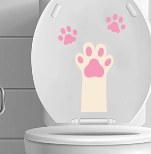 Close-up of waterproof PVC cat paw stickers applied on a white toilet lid in a bathroom